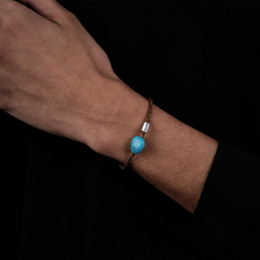 Close-up of a model's wrist wearing the woven Tibetan turquoise anchor bracelet for emotional balance.