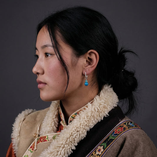Side profile of a model wearing the Serene Drops Tibetan turquoise sphere earrings for a peaceful look.