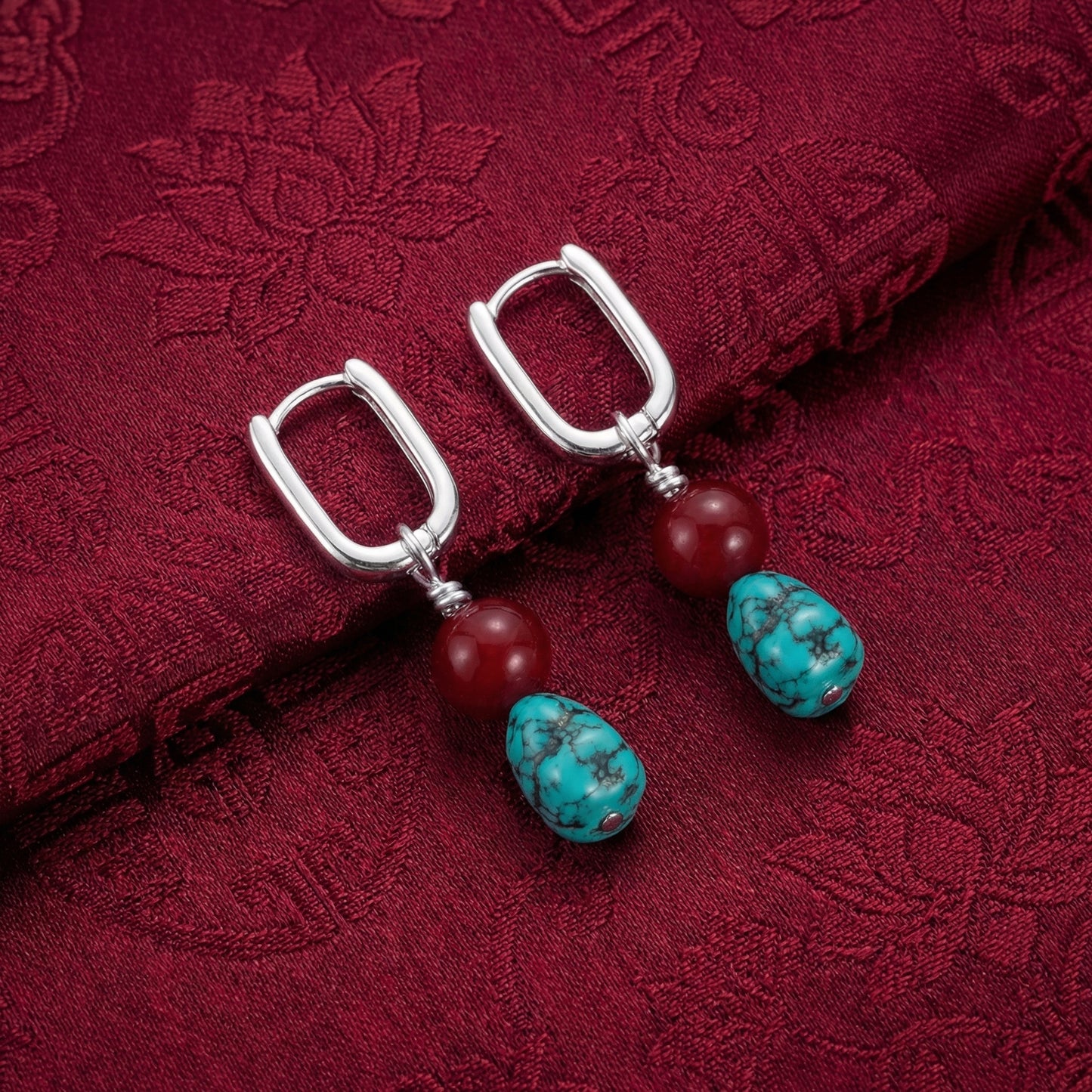 The Abundance Drops displayed on traditional dark red silk fabric, reflecting Himalayan heritage and auspicious blessings.