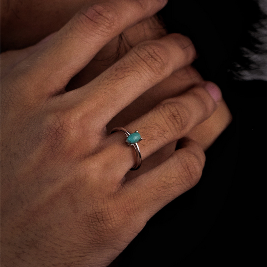 Close-up of a model's hand wearing the Stillness turquoise ring in a meditation pose.