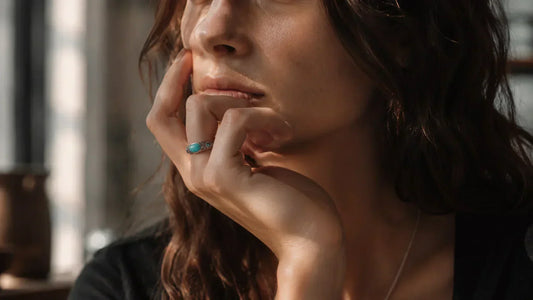 A thoughtful woman wearing a turquoise wrap ring, illustrating the protection ring meaning as a boundary ritual and spiritual jewelry for daily mindfulness.