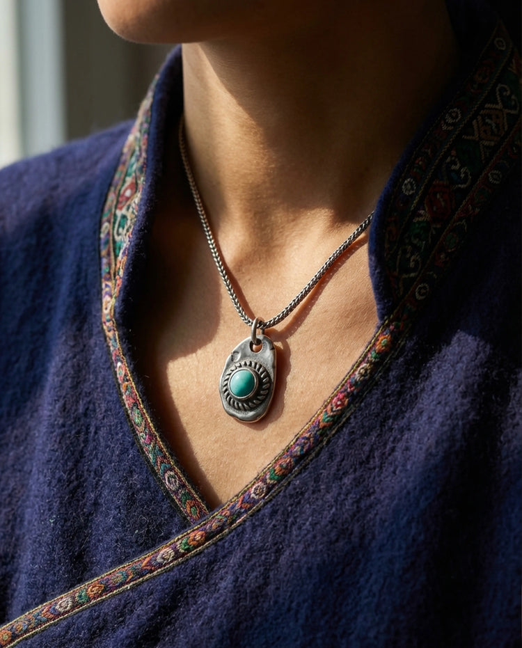 An authentic Tibetan turquoise amulet resting on textured brown yak wool, representing sacred artifacts of faith.