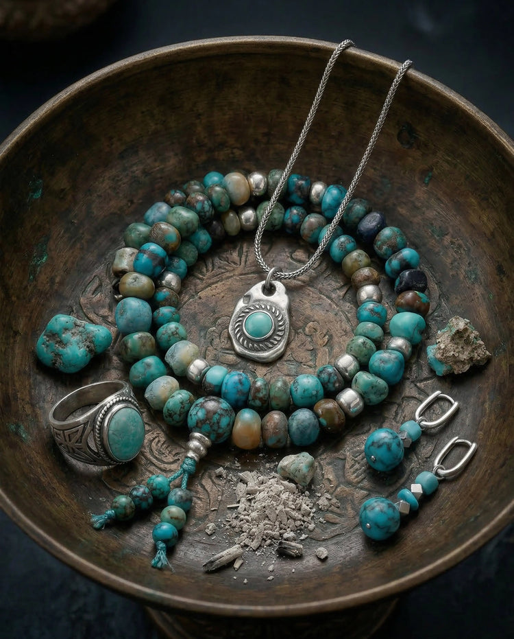 A dynamic editorial flat lay showcasing an assortment of all types of authentic Tibetan turquoise jewelry, including necklaces, rings, and bracelets, artfully arranged on raw Himalayan slate stone, representing the entire Earth's Offerings Collection.