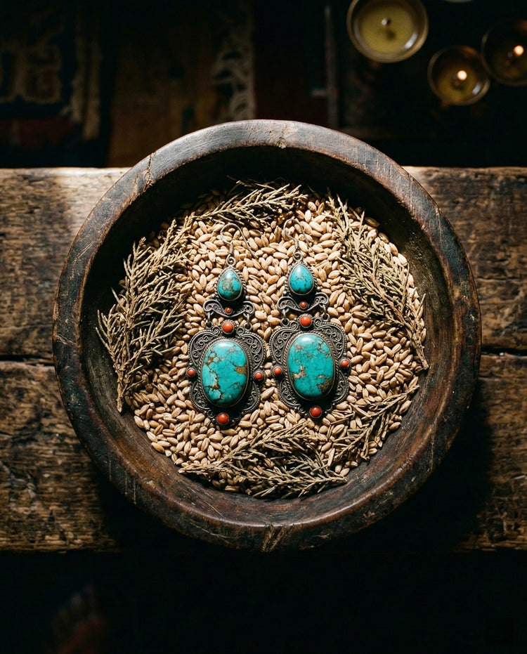A pair of vibrant Tibetan turquoise drop earrings resting inside a rustic bronze offering bowl, symbolizing abundance and the Fulfillment Collection.