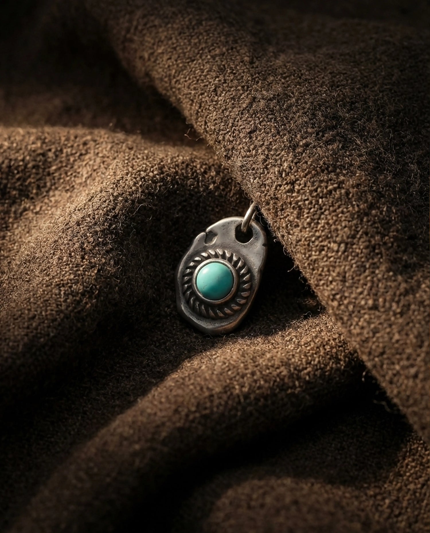 A person wearing a handcrafted Tibetan turquoise pendant necklace paired with a traditional indigo blue garment.