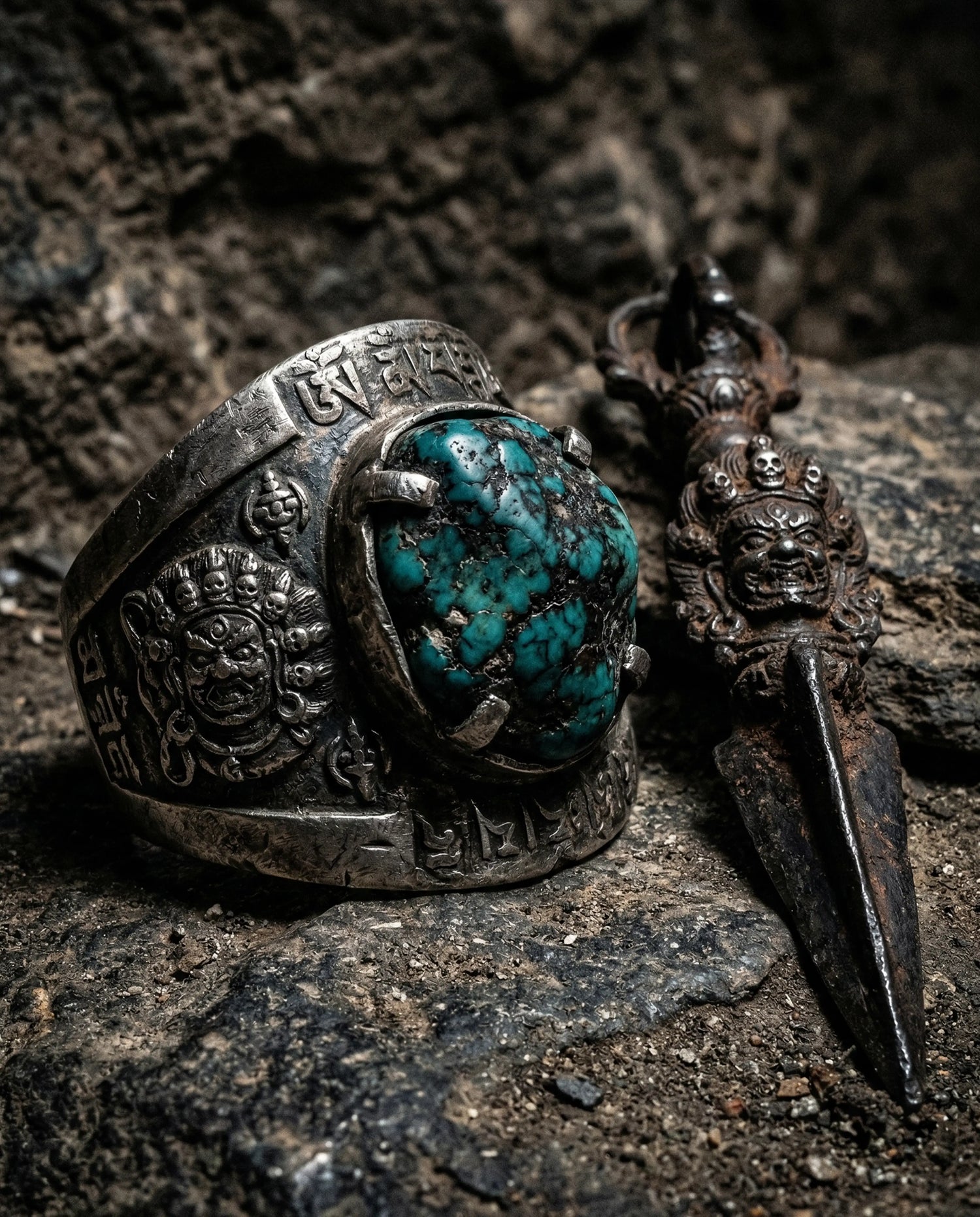 A handcrafted oxidized silver Tibetan turquoise ring resting on dark rough stone, representing the protective energy of the Protection Collection.