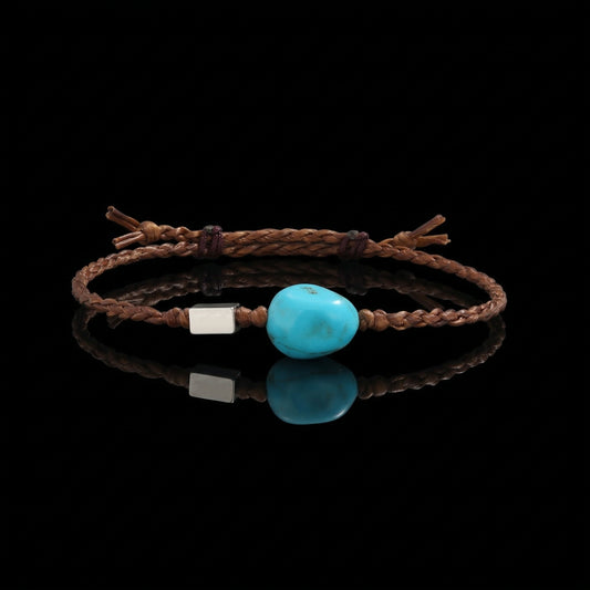 The Anchor Bracelet featuring a freeform Tibetan turquoise stone on a hand-braided brown cord.