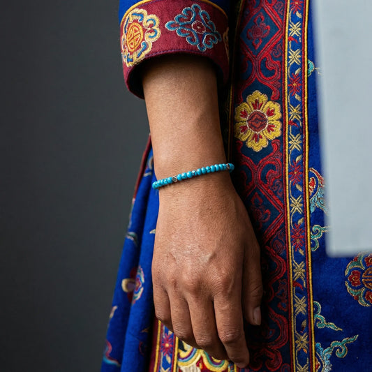 Close-up of a model's wrist wearing the Clear Sky turquoise bracelet with traditional Himalayan dress.