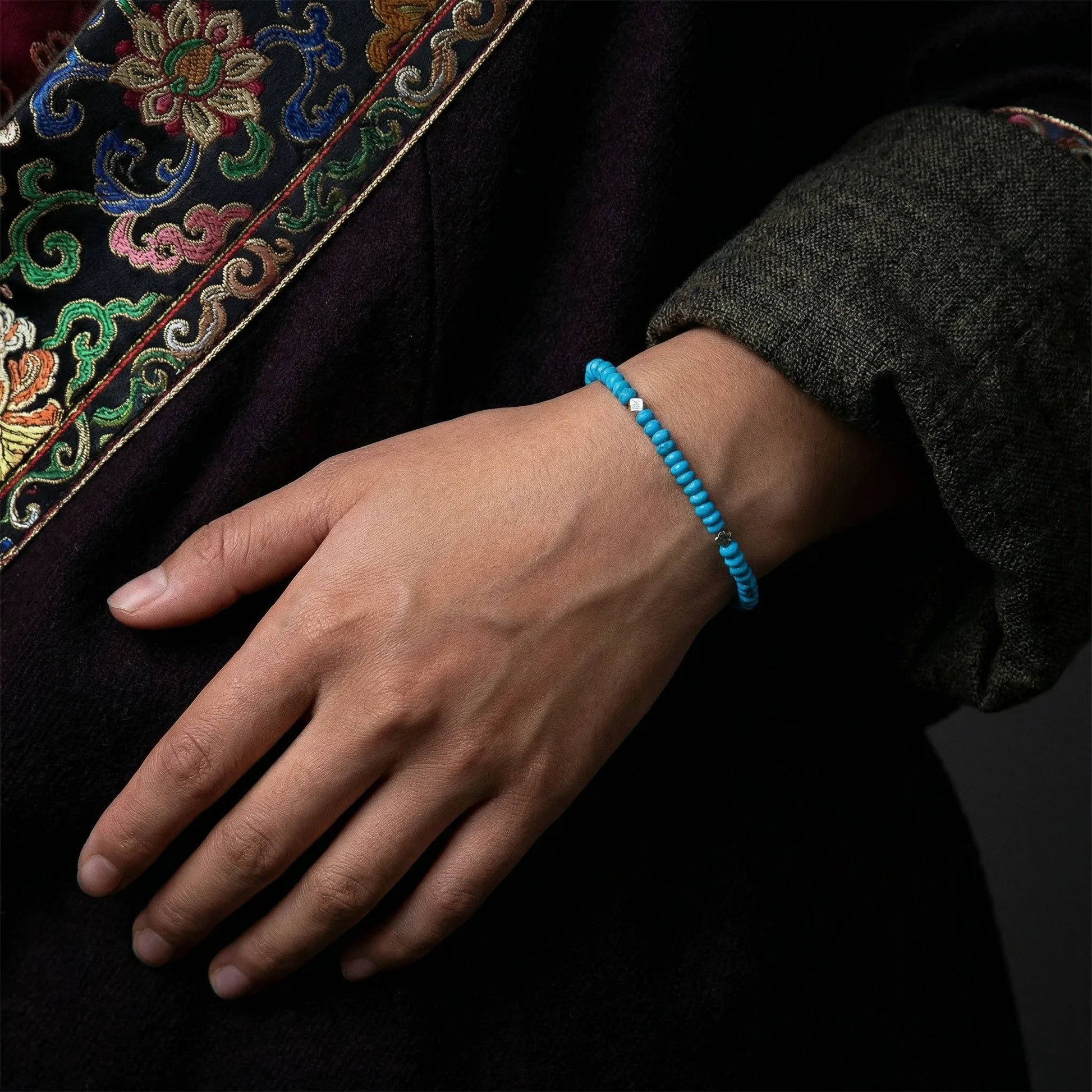 A model's hand resting gracefully, wearing the Clear Sky Tibetan turquoise bracelet for spiritual grounding.