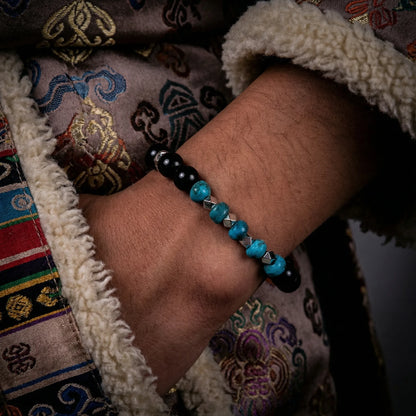 A model wearing the Eclipse Tibetan turquoise bracelet, showcasing its contrast against dark textures.