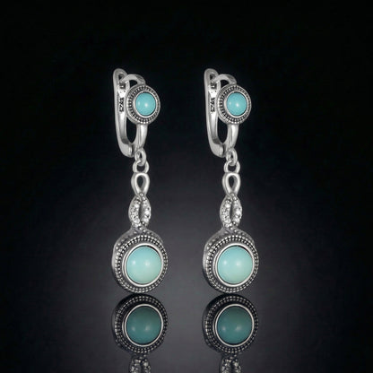 The Eternal Drops featuring dual round Tibetan turquoise stones and vintage-inspired silver milgrain halos.