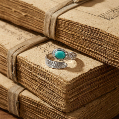 The Insight Feather Ring displayed on ancient weathered Tibetan books, reflecting a heritage of wisdom.