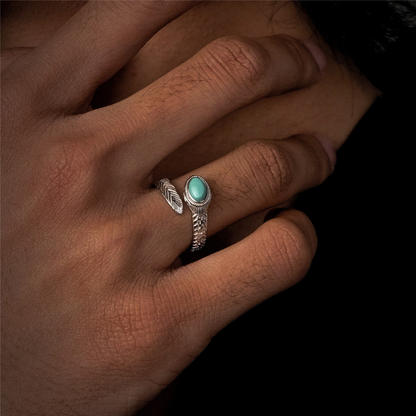 Perspective view of the Insight Feather turquoise ring on a finger against a dark background.