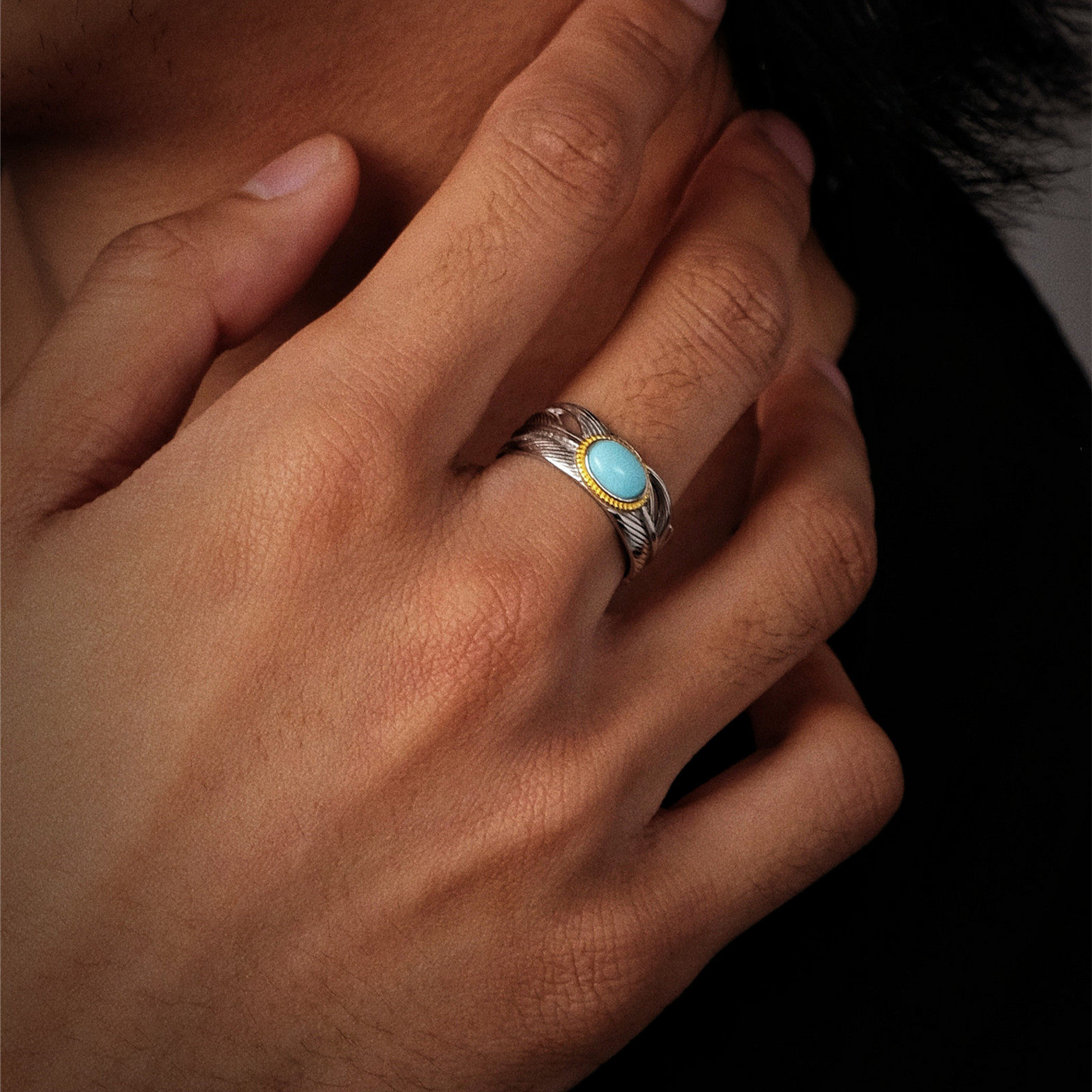 Perspective view of the Guardian Wing turquoise ring on a finger, showcasing its detailed plumage texture.