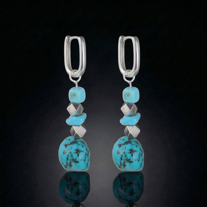 The Grounding Drops featuring a cascade of Tibetan turquoise nuggets, silver cube spacers, and U-shaped silver hoops.