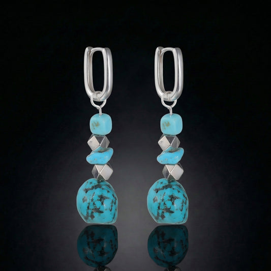 The Grounding Drops featuring a cascade of Tibetan turquoise nuggets, silver cube spacers, and U-shaped silver hoops.