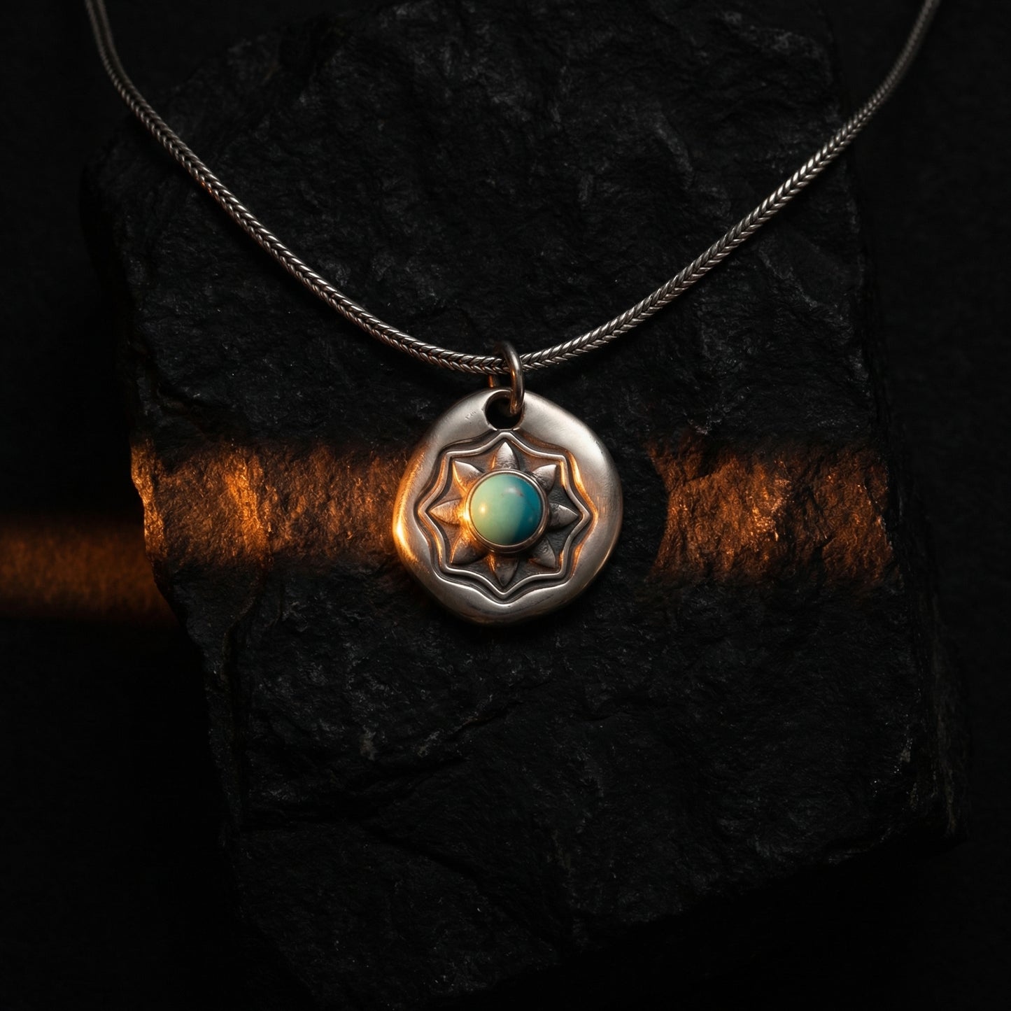 Detailed texture of the handcrafted starburst shield pendant with a vibrant blue stone.