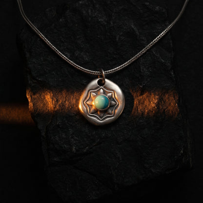 Detailed texture of the handcrafted starburst shield pendant with a vibrant blue stone.