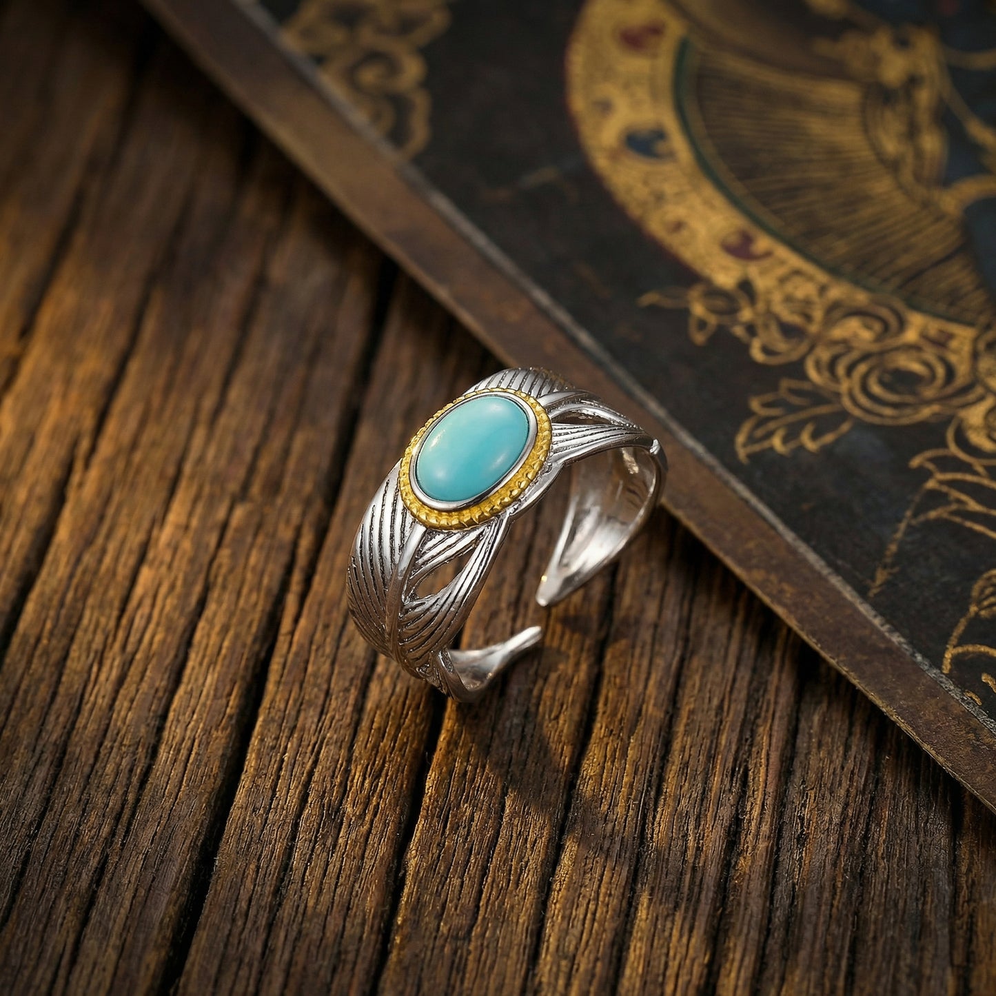 The Guardian Wing Ring displayed on a vintage Tibetan manuscript and rustic wood, reflecting heritage.