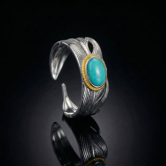The Guardian Wing Ring featuring an oxidized silver wing motif and oval Tibetan turquoise in a gold bezel.