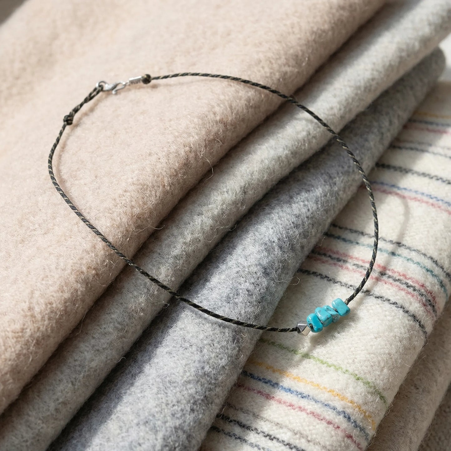The Silent Pulse woven necklace displayed on soft neutral textiles, reflecting Himalayan heritage and comfort.