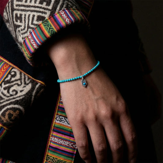 Close-up of a model's wrist wearing the delicate Sun Shield turquoise bracelet with traditional attire.