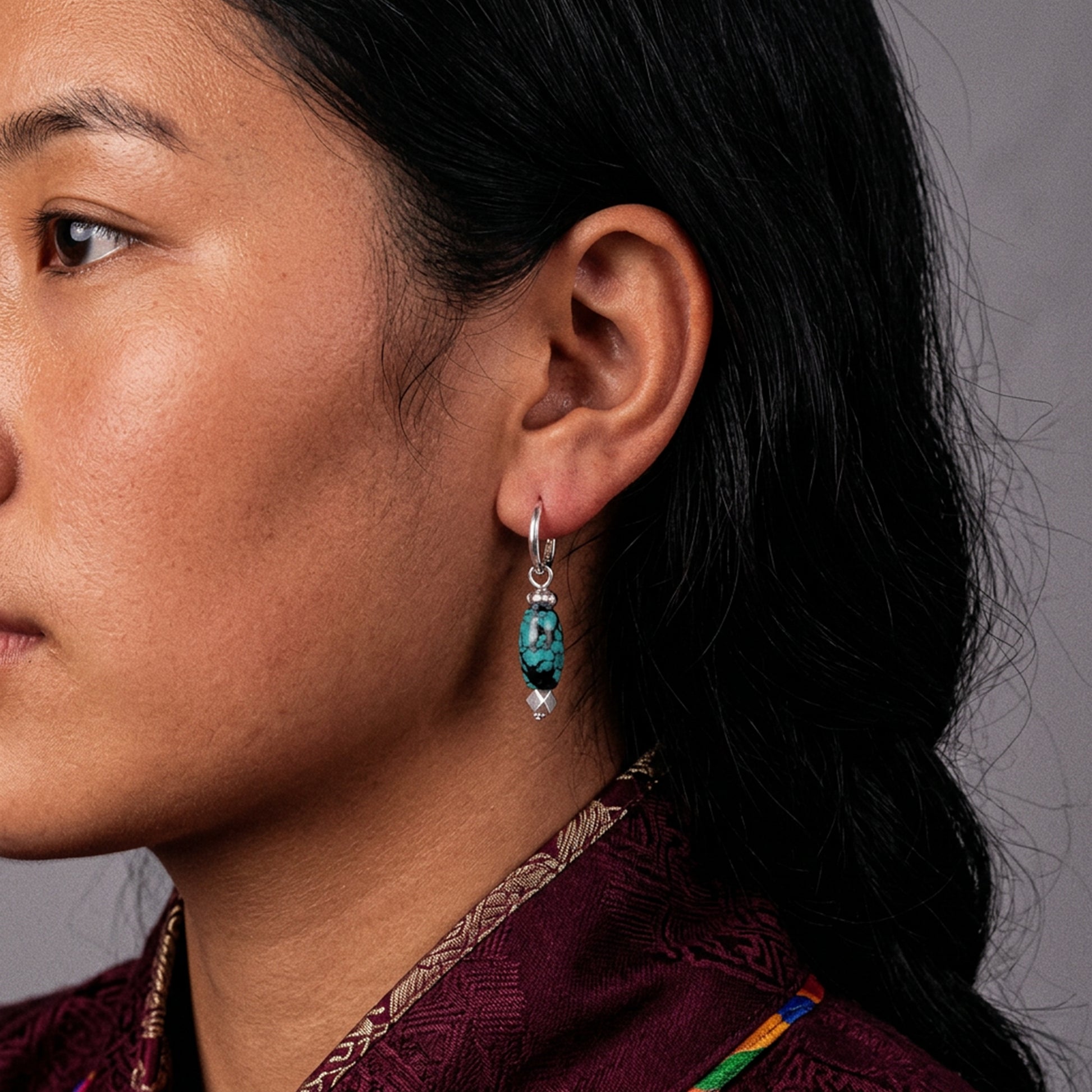 Close-up profile of a model wearing the structural Tibetan turquoise drop earrings for spiritual protection.