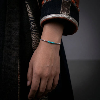 Close-up of a model's wrist wearing the silver bead and turquoise loop bracelet, reflecting a minimalist aesthetic.