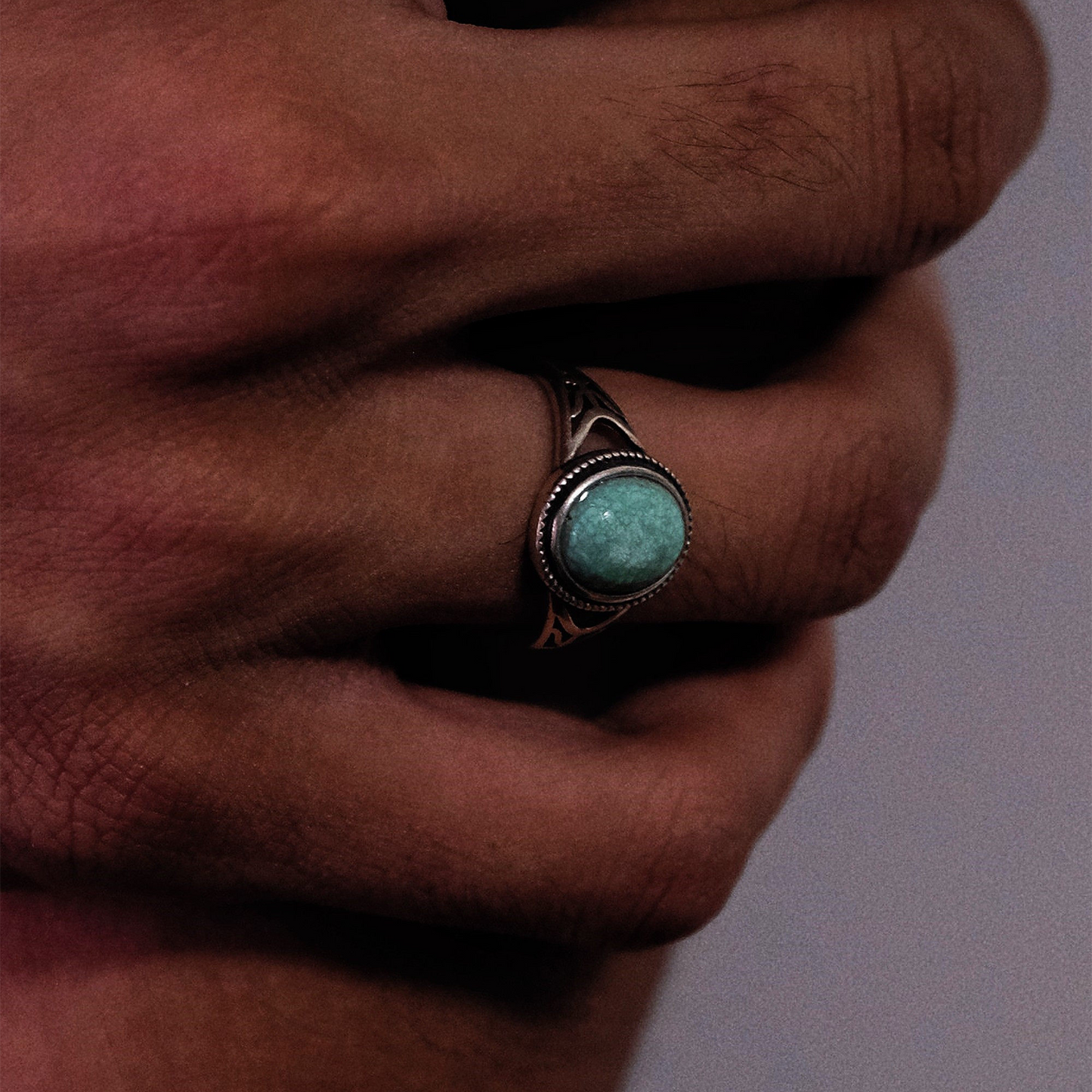 Perspective view of the openwork silver turquoise ring on a finger, showcasing its structural design.