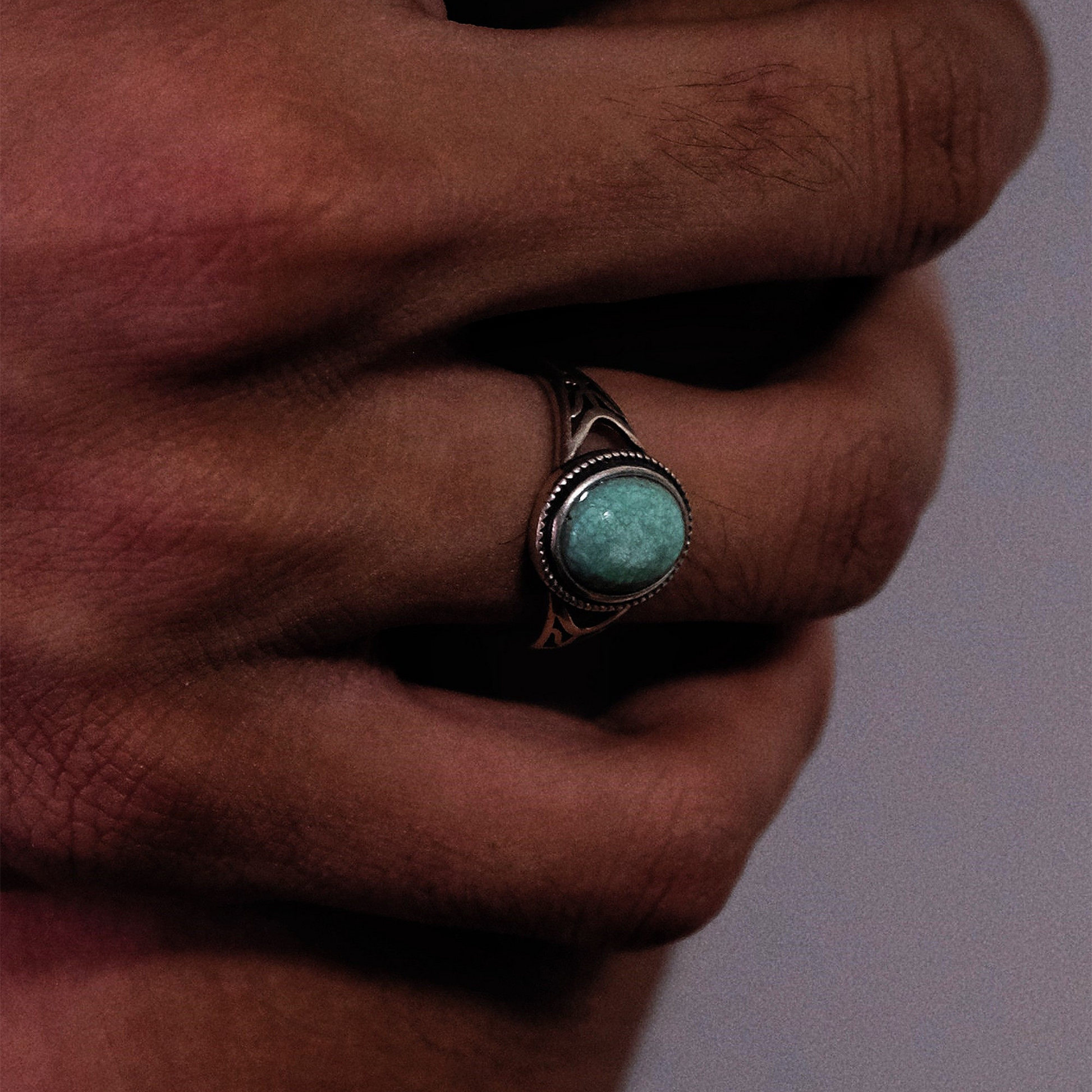 Perspective view of the openwork silver turquoise ring on a finger, showcasing its structural design.