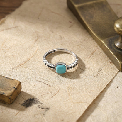 The Rational Link ring displayed on a piece of vintage handmade paper near a bronze ornament.