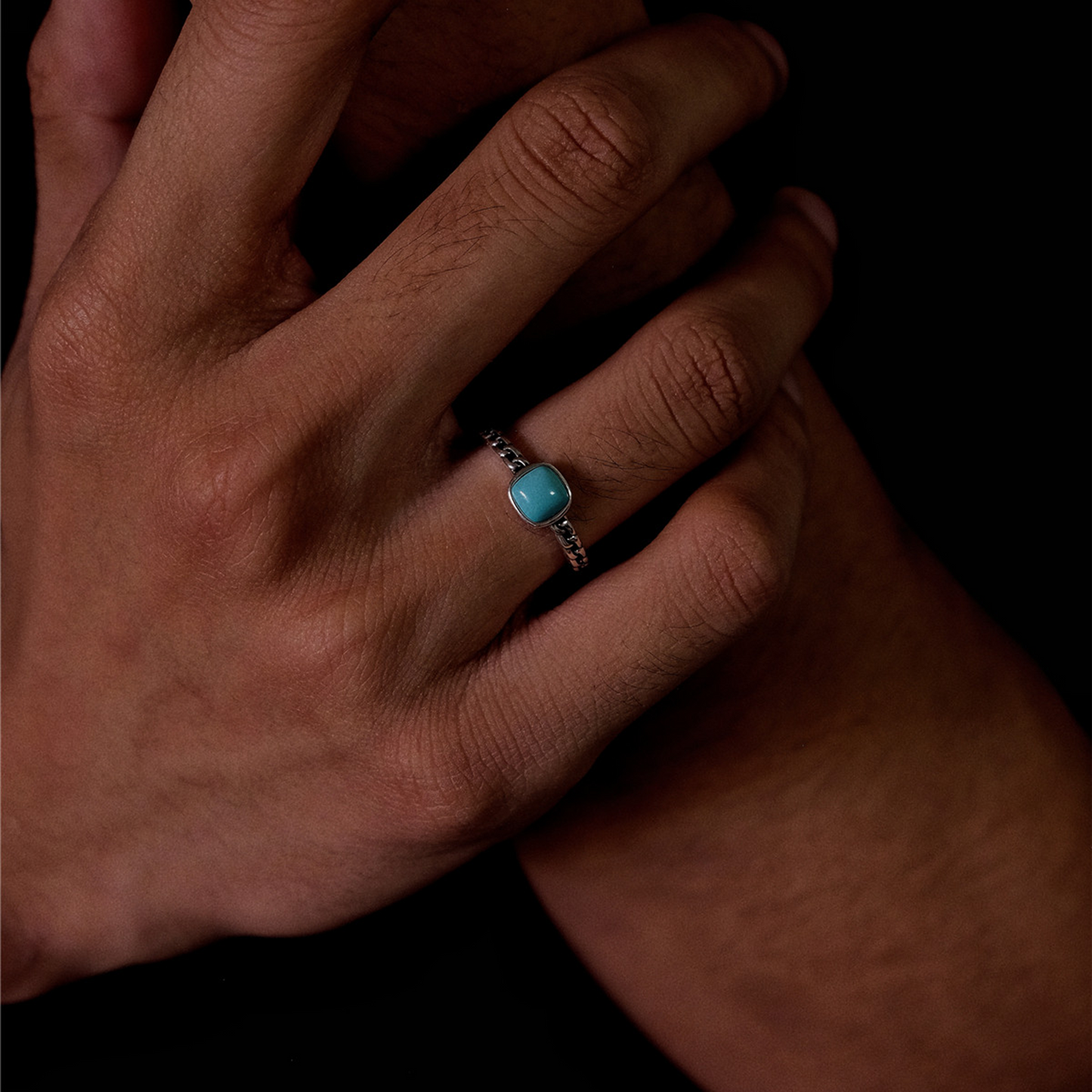 Detail shot of the Rational Link ring on a model, highlighting the vibrant blue stone and silver links.