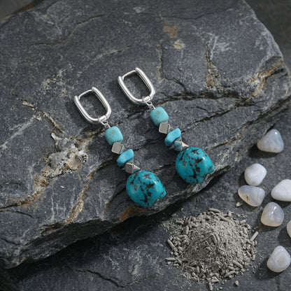 The Grounding Drops displayed on dark slate stone with cedarwood powder, reflecting Himalayan heritage and earth connection.