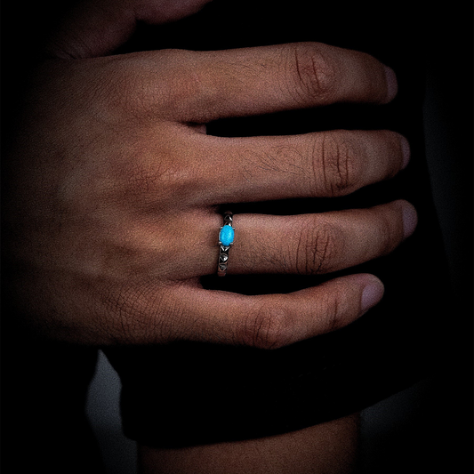Close-up of a model's hand wearing the vertical turquoise Ridge ring against a dark background.