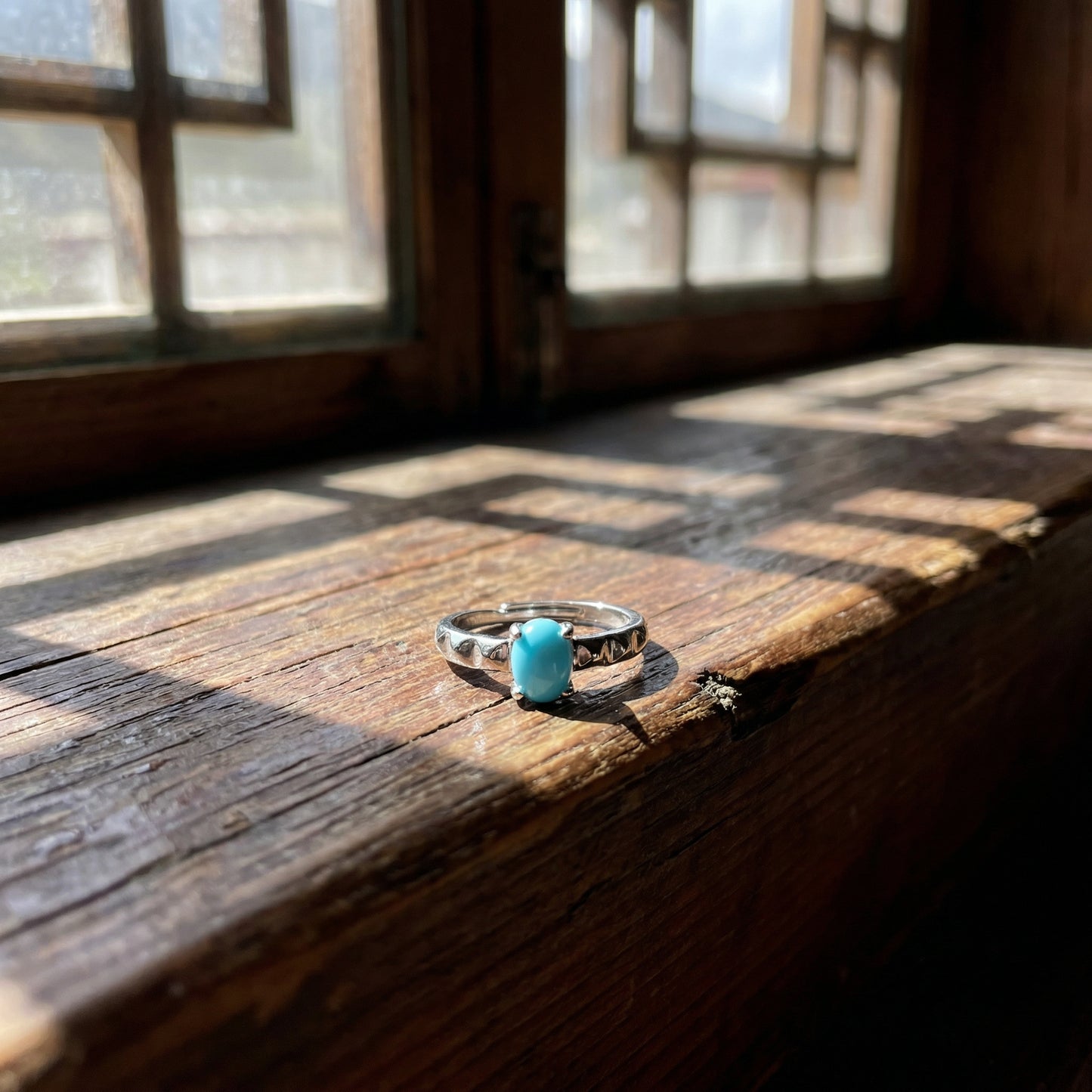 The Ridge Ring displayed on a weathered wooden window sill in natural sunlight, reflecting mountain calm.