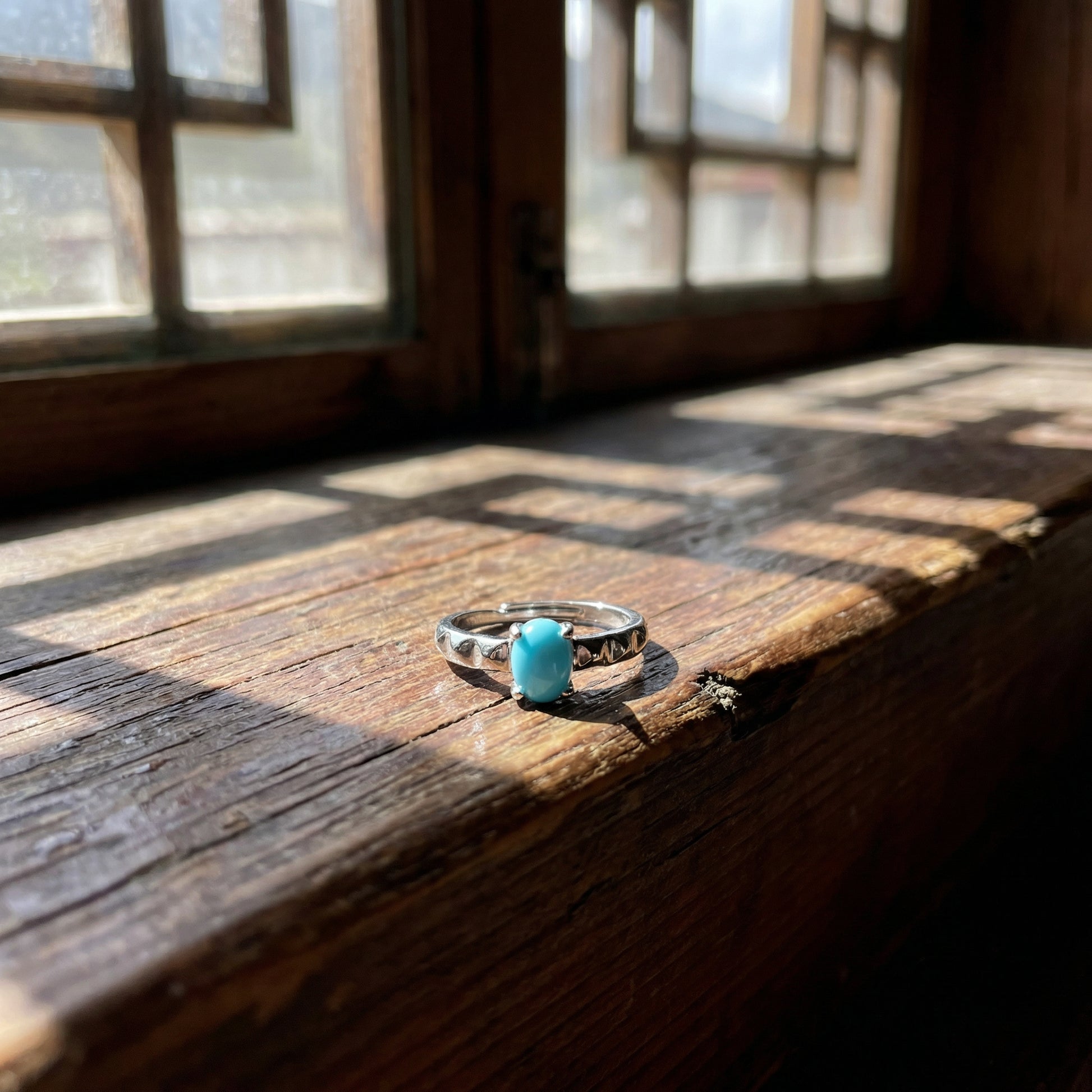 The Ridge Ring displayed on a weathered wooden window sill in natural sunlight, reflecting mountain calm.