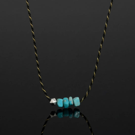 The Silent Pulse Choker featuring raw Tibetan turquoise chips and a geometric silver bead on a woven cord.