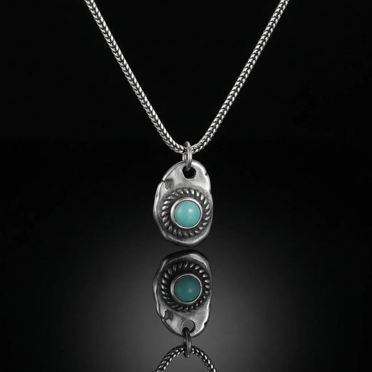 The Solar Amulet Necklace featuring an organically shaped silver pendant with a round Tibetan turquoise stone.