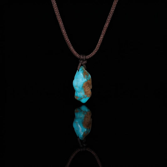The Solitary Stone Necklace featuring a raw Tibetan turquoise nugget on a brown woven cord.