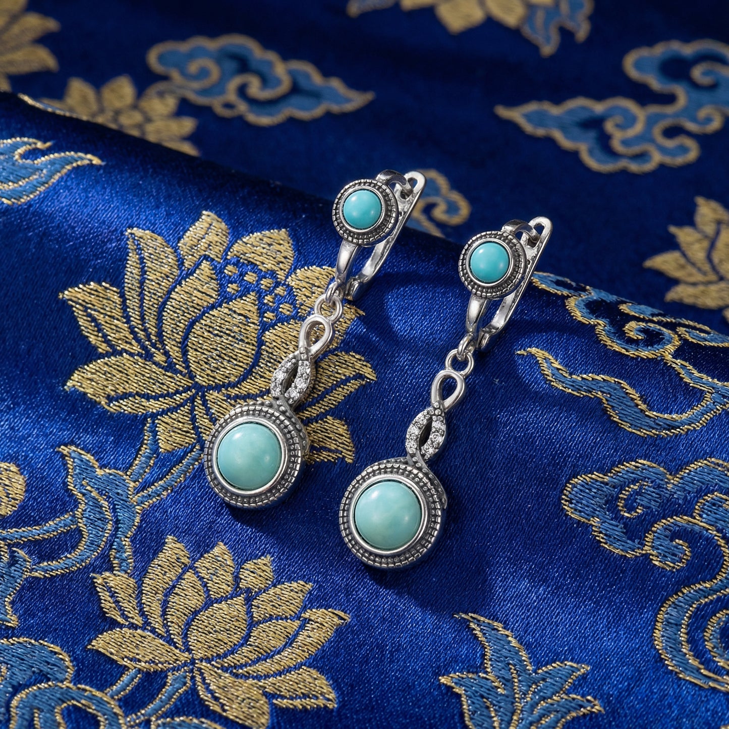 The Eternal Drops displayed on traditional blue silk with lotus motifs, reflecting Himalayan heritage and blessings.