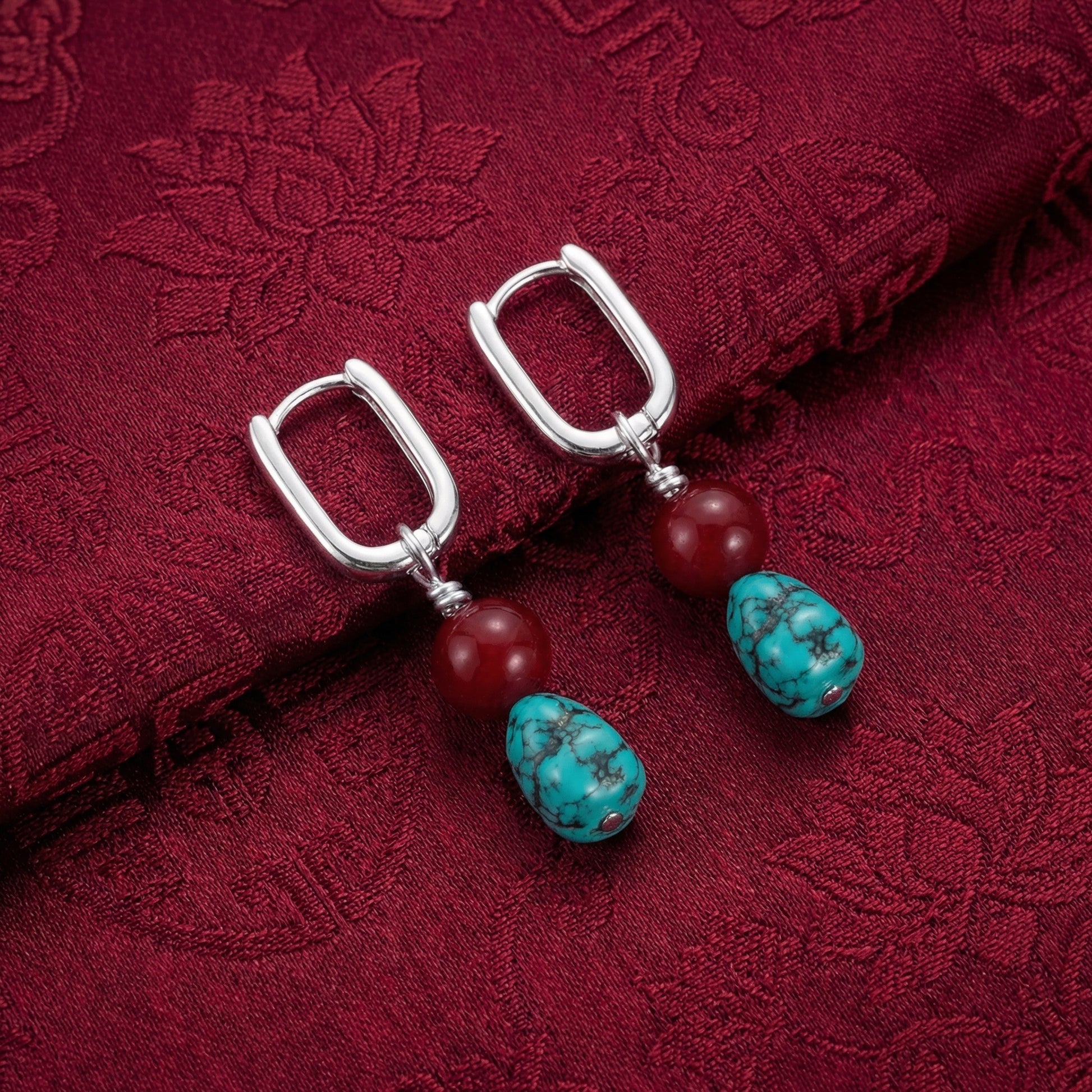 The Abundance Drops displayed on traditional dark red silk fabric, reflecting Himalayan heritage and auspicious blessings.