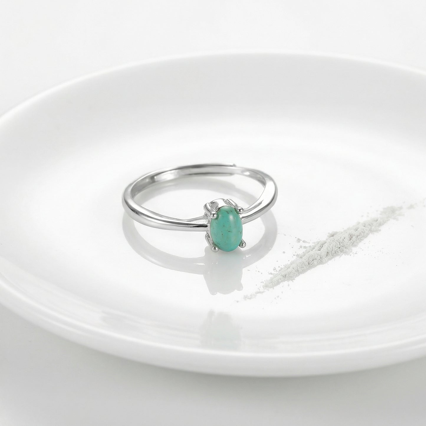The Stillness Ring displayed on a white ceramic plate with a ritual powder line, reflecting purity and calm.