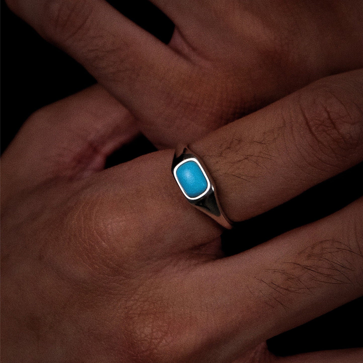 Model with clasped hands wearing the turquoise Stillwater signet ring, reflecting stability.