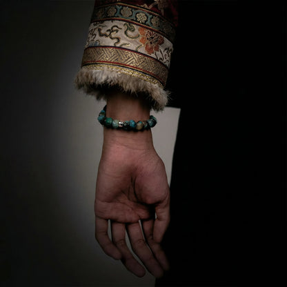 Side view of the substantial turquoise and dark stone bracelet on a wrist, highlighting its tactile weight.