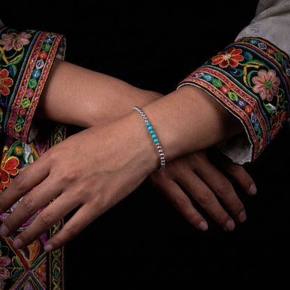 Two hands holding the silver bead healing bracelet, emphasizing its tactile quality and meditative nature.