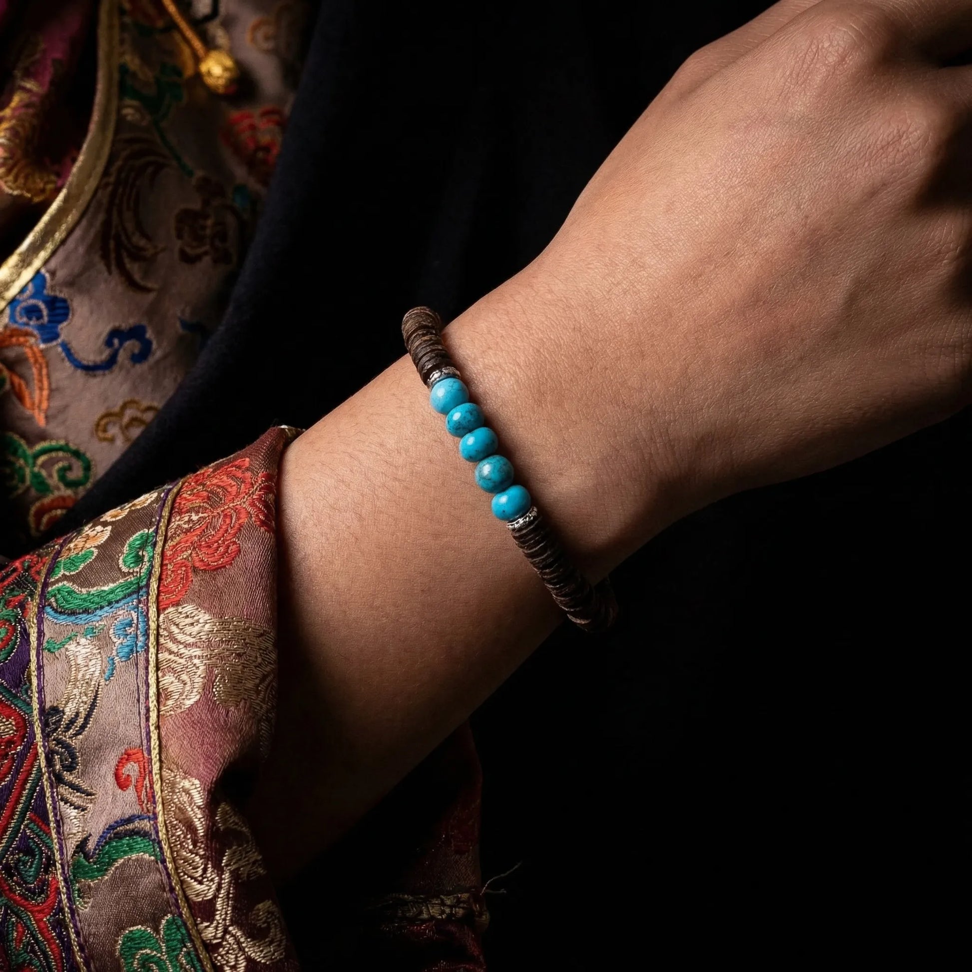 Detailed view of the turquoise grounding bracelet on a wrist, styled with traditional Himalayan-inspired attire.