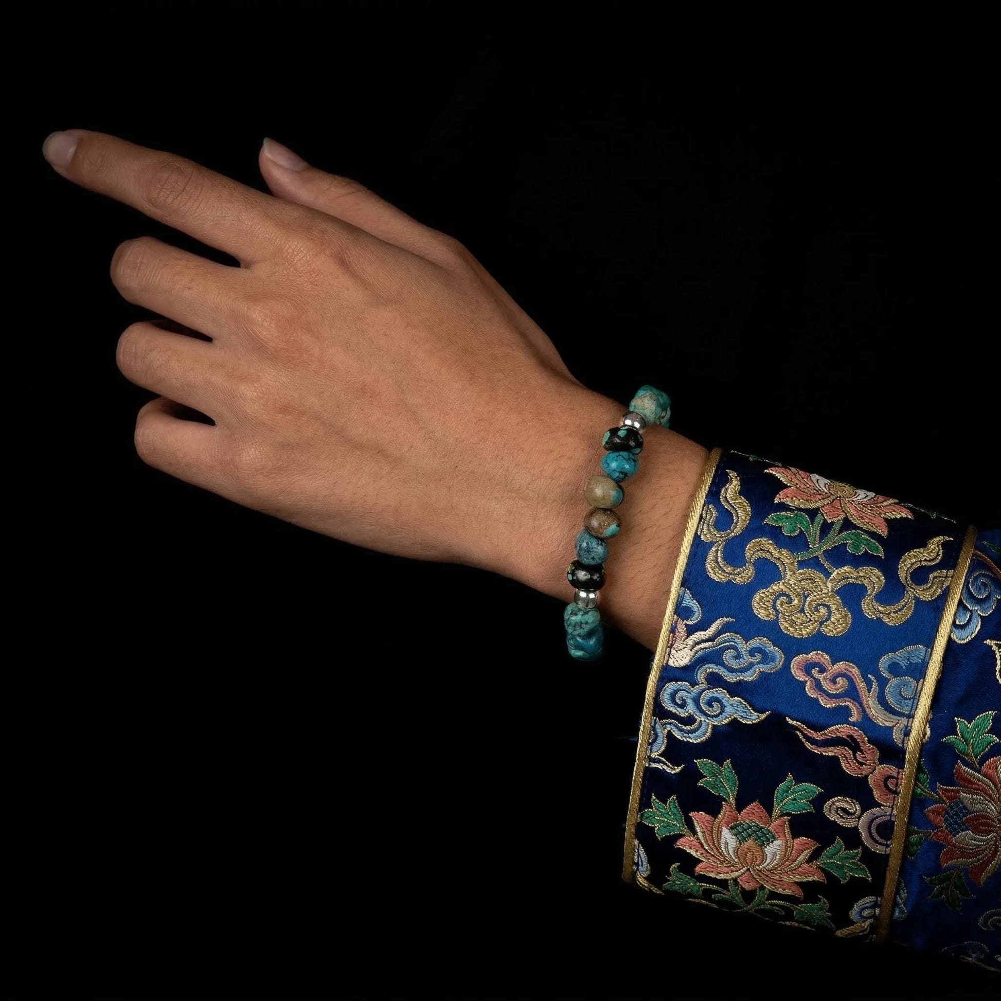 A model's hand resting on their lap, wearing the Pilgrim's Path bracelet for spiritual protection.