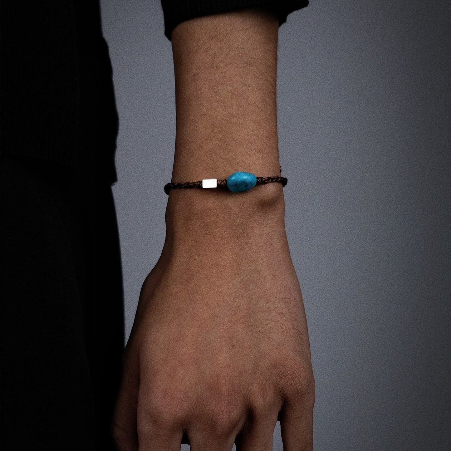 Side view of the natural turquoise woven bracelet on a wrist, highlighting the silver accent and braid texture.