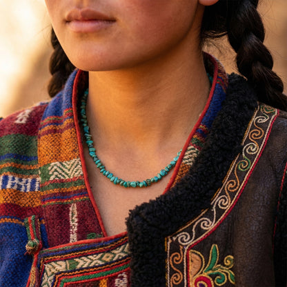Close-up of a model wearing the turquoise chip necklace in warm sunlight, showcasing the organic blue-green tones.